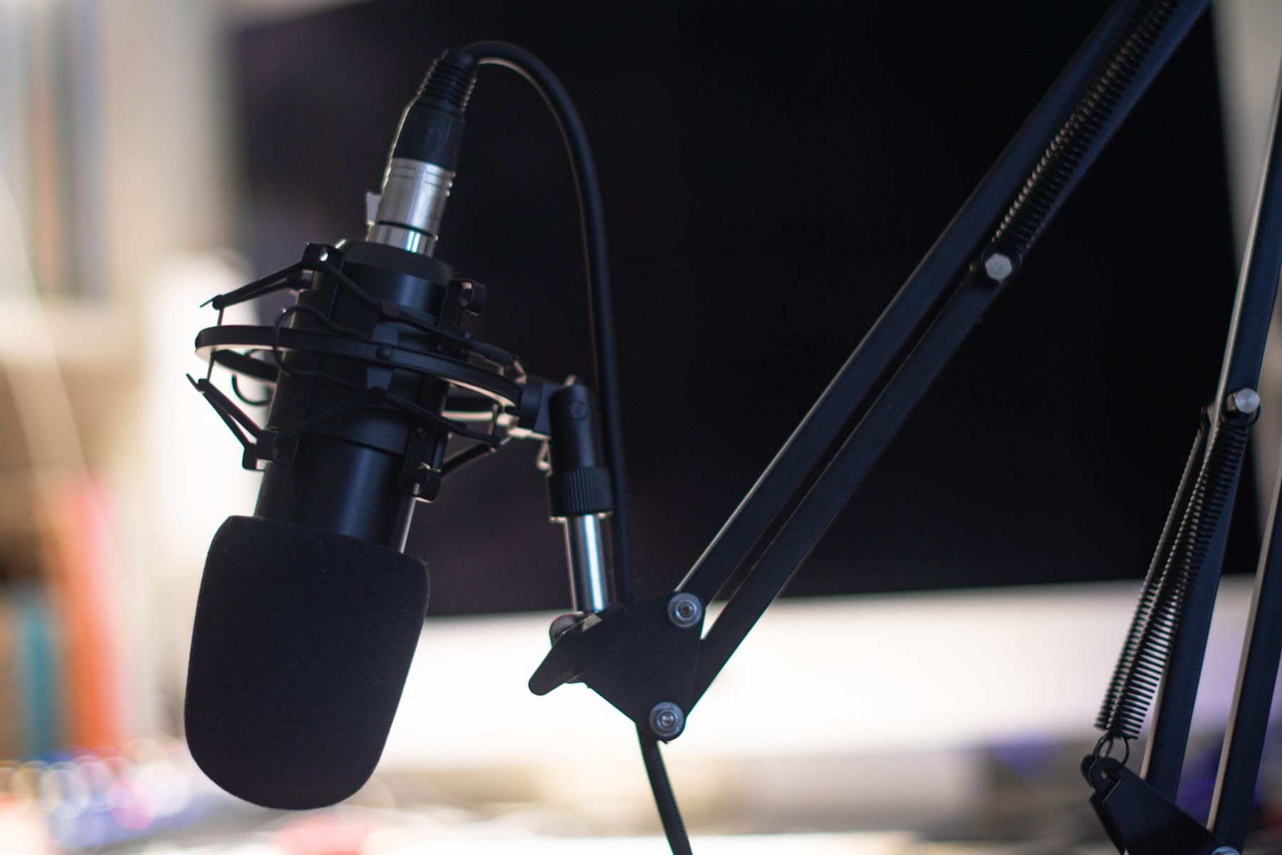 A condenser microphone on a boom arm in a recording studio.
