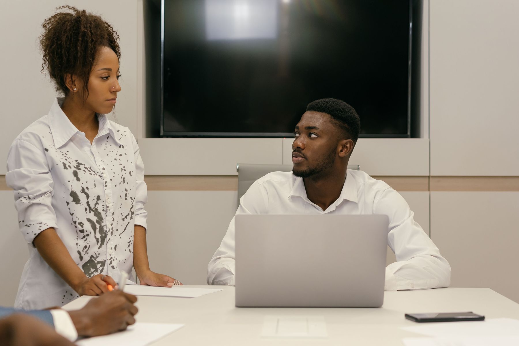 Two colleagues working together at a laptop in a conference room.