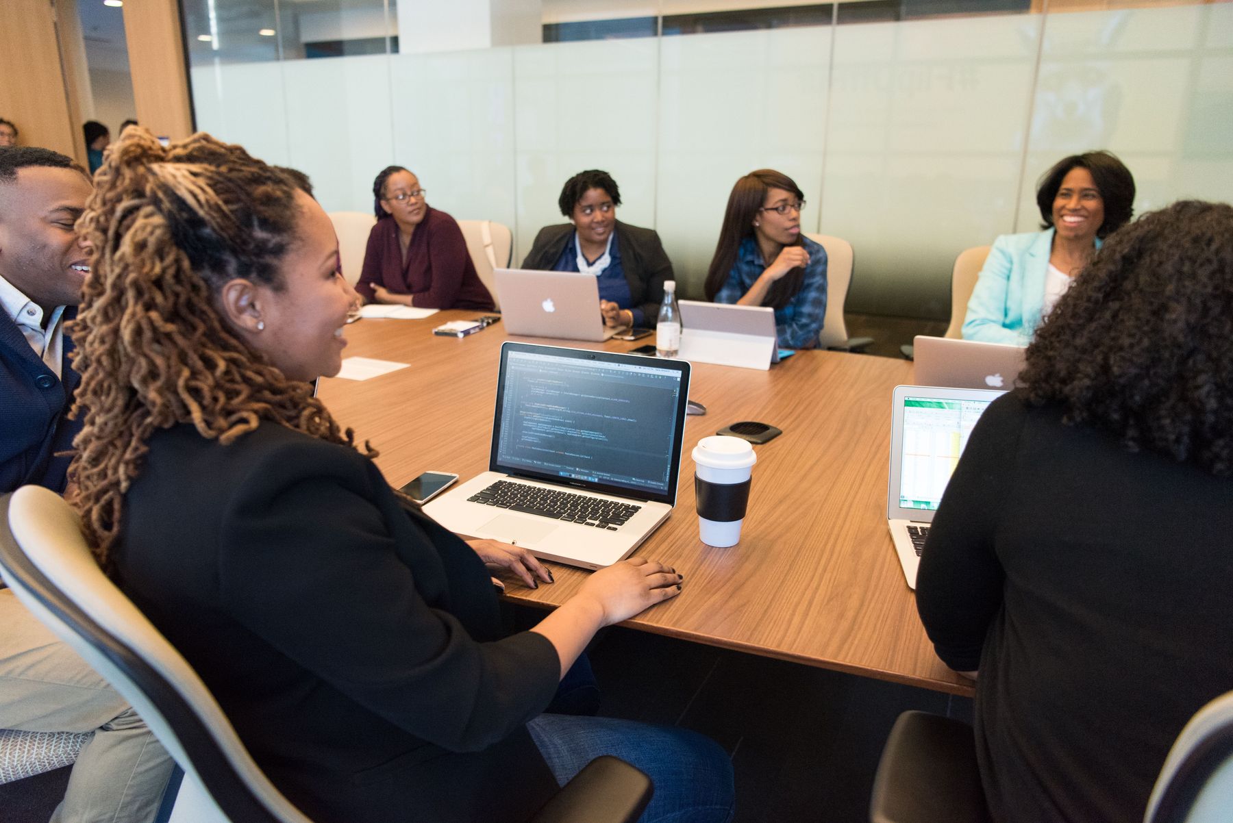 A group of professionals around a boardroom table with laptops and notes.